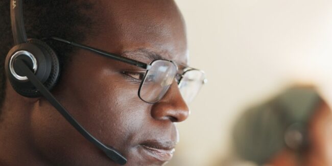 Close-up, side-view image of a man with glasses and a headset with a thoughtful look on his face.