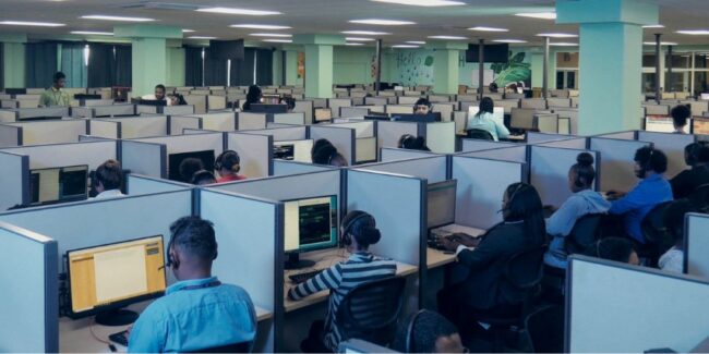 A large room of cubicles with agents seated in each cubicle answering phone calls.