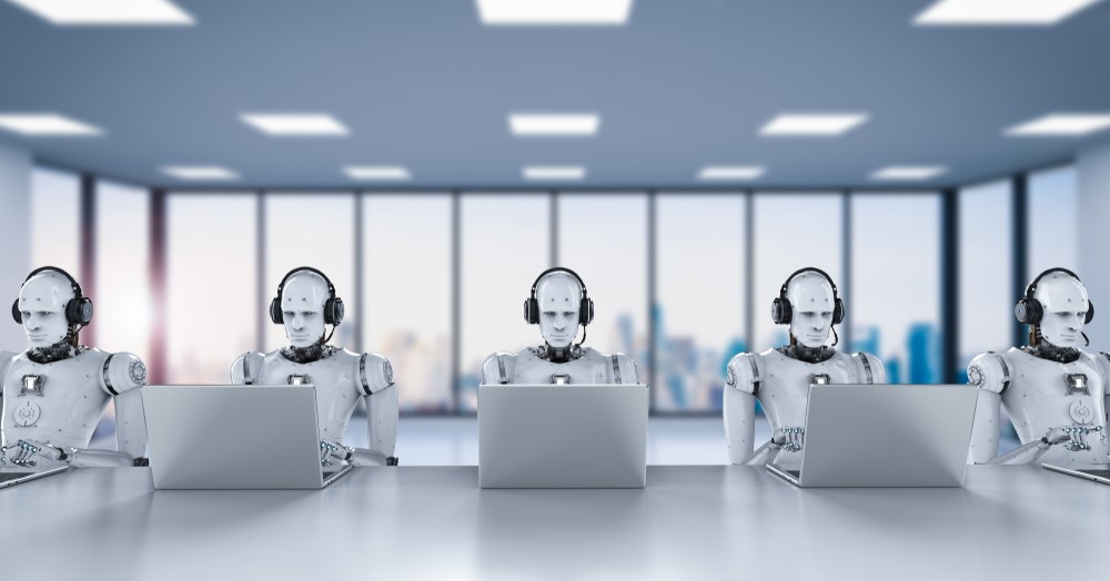 A row of white robots sits at a table, each in front of a laptop.